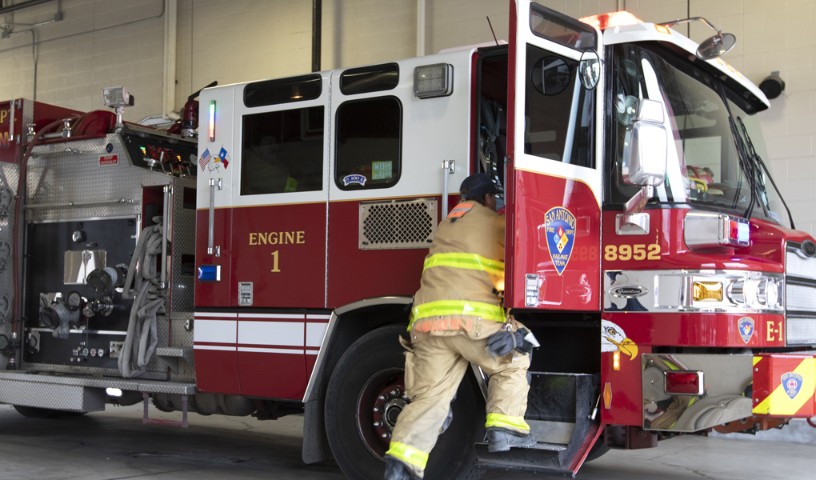 Fireman jumping into firetruck, responding to an emergency