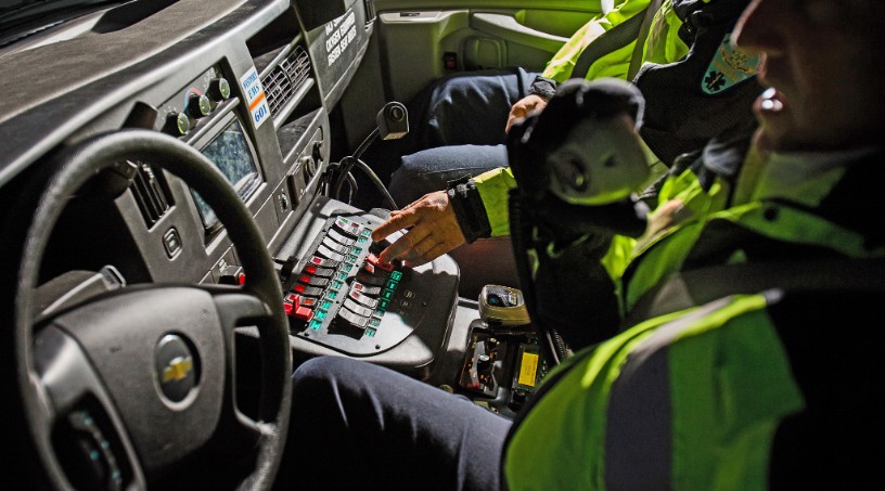 First responders in a car talking on a radio. 